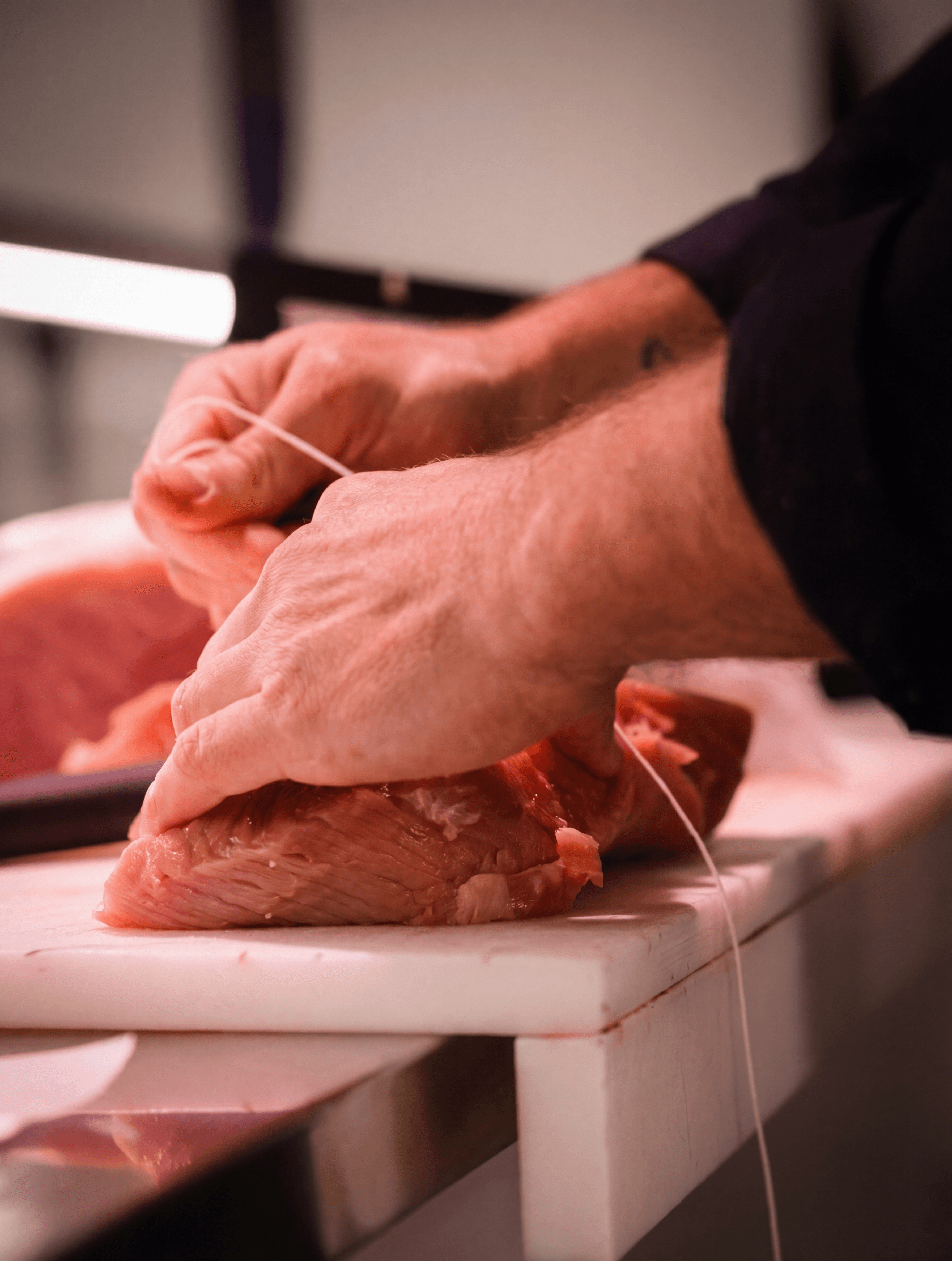 Mains d'artisan ficelant une pièce de viande, Boucherie Labourde Perpignan